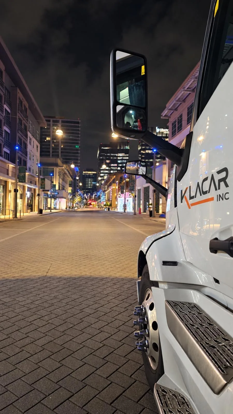 View from the cab of a Klacar truck on a city street at night