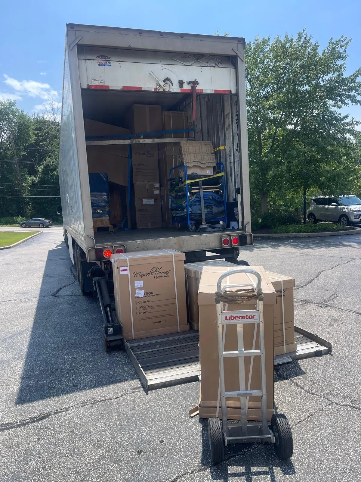 Boxes and a hand truck at the open door of a Klacar trailer