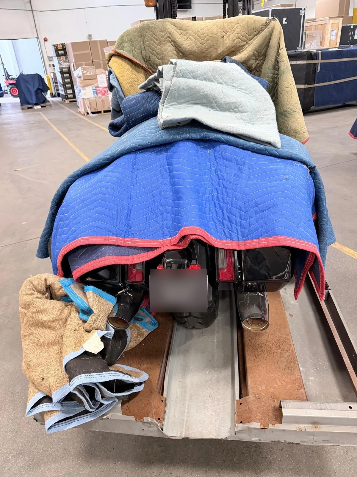 A Harley-Davidson motorcycle blanket-wrapped on a skid